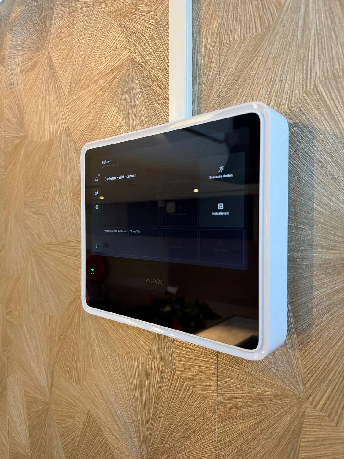 Bedienscherm van een alarmsysteem aan de wand, met de melding dat het systeem normaal werkt