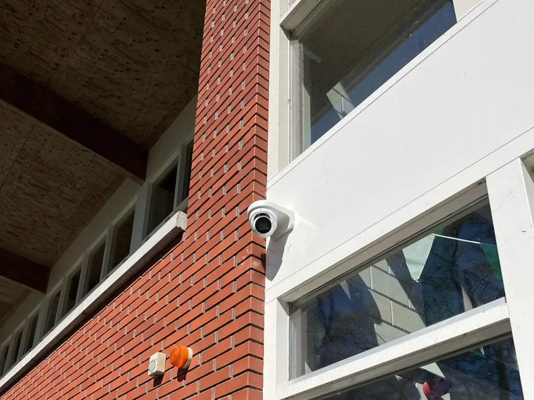 Dome-camera aan de bakstenen gevel van een clubgebouw met grote ramen
