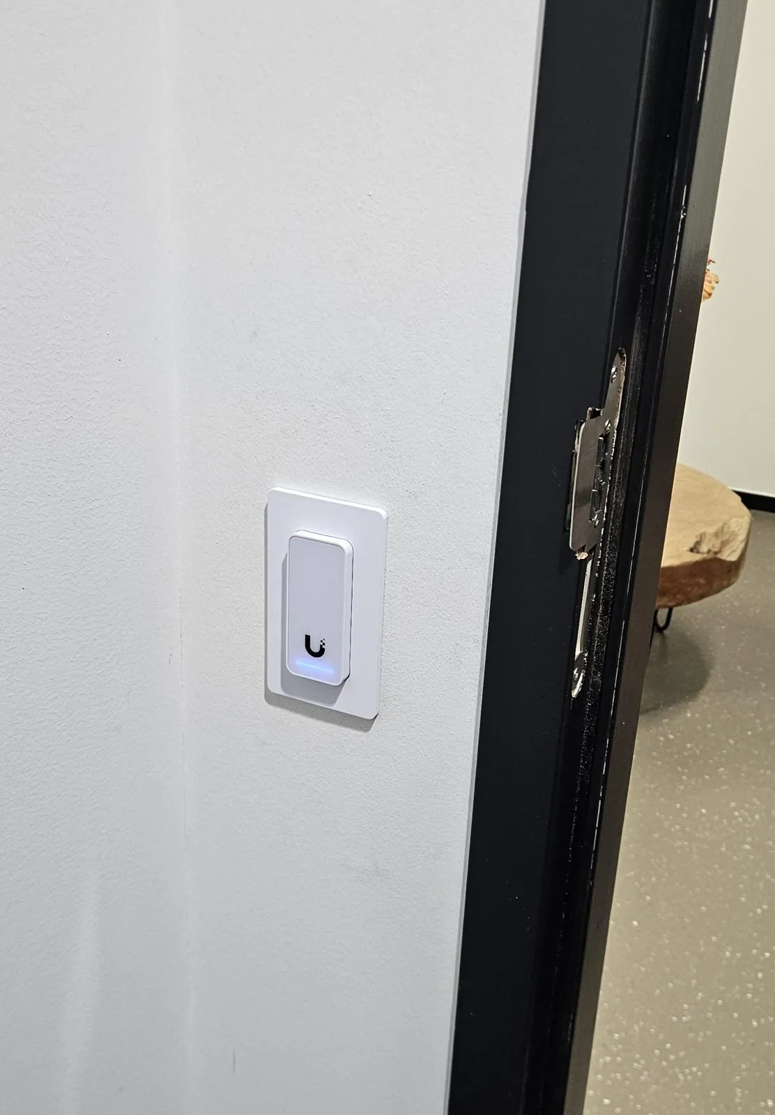 Toegangslezer met blauw lampje in een gipswand naast een zwart kozijn